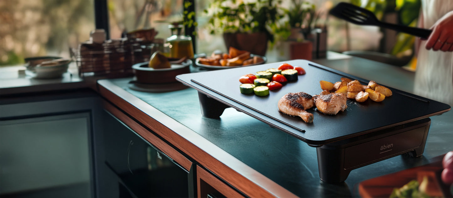 Plită cu mâncare pe blatul bucătăriei, înconjurată de ustensile de bucătărie.